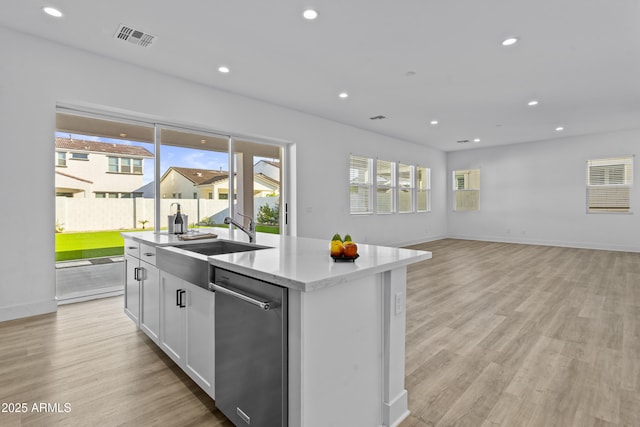 kitchen with a sink, light wood-style flooring, a kitchen island with sink, and recessed lighting