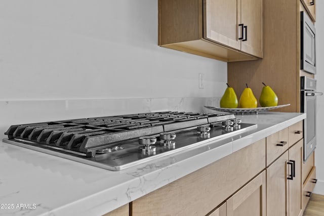 kitchen with light brown cabinets, stainless steel appliances, light countertops, and wood finished floors