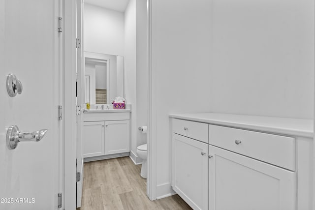 bathroom featuring toilet, vanity, and wood finished floors