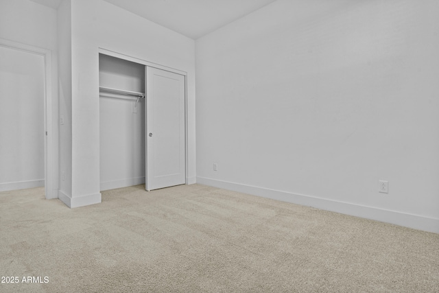 unfurnished bedroom featuring carpet flooring, baseboards, and a closet