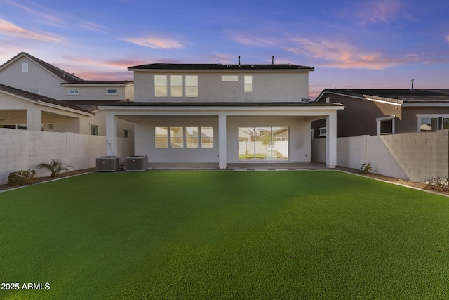 rear view of house with stucco siding, central air condition unit, a fenced backyard, and a patio area