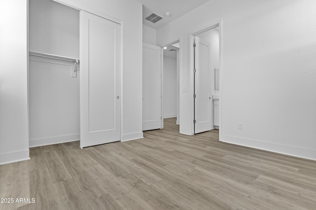 unfurnished bedroom featuring a closet, visible vents, light wood-type flooring, and baseboards