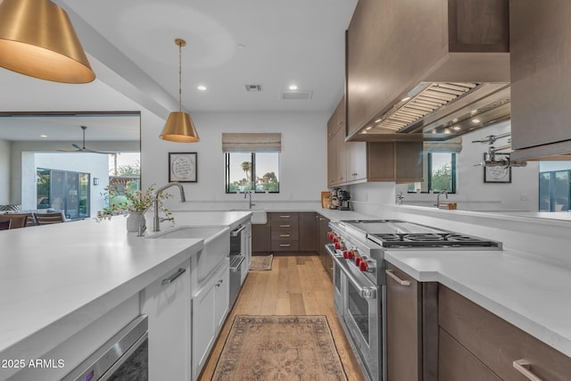 kitchen featuring visible vents, light countertops, light wood-style floors, high end stainless steel range, and wall chimney exhaust hood