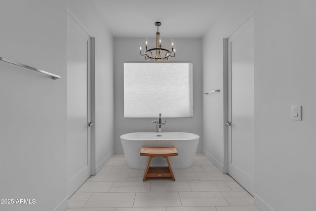 bathroom with a soaking tub, baseboards, and an inviting chandelier