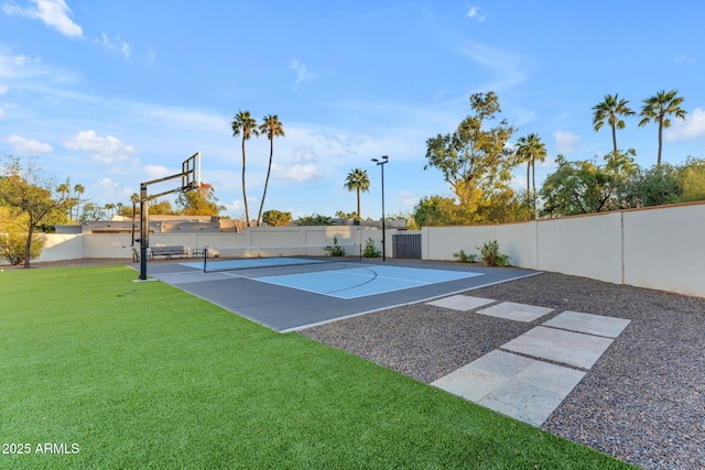 view of basketball court featuring a fenced backyard, a lawn, and community basketball court