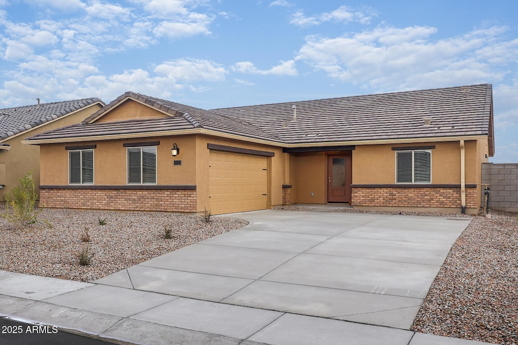 ranch-style home featuring an attached garage, stucco siding, driveway, and brick siding