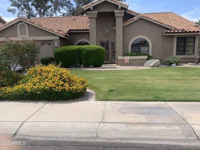 mediterranean / spanish-style home with stucco siding, a tiled roof, a front yard, and a garage