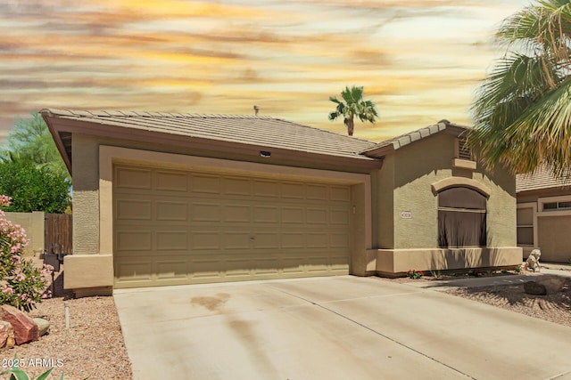view of front of home with a garage, stucco siding, concrete driveway, and a tiled roof