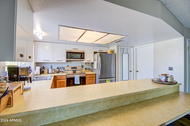 kitchen with stainless steel appliances, a textured ceiling, sink, and white cabinets