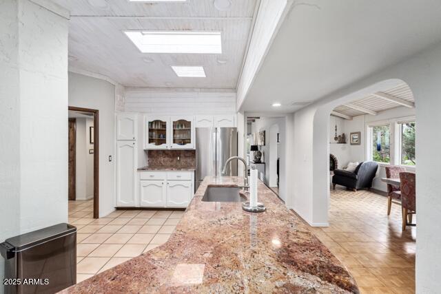 25 Edgewood Cir, Sedona, AZ 86336 - kitchen with a sink, freestanding refrigerator, white cabinetry, arched walkways, and light tile patterned flooring