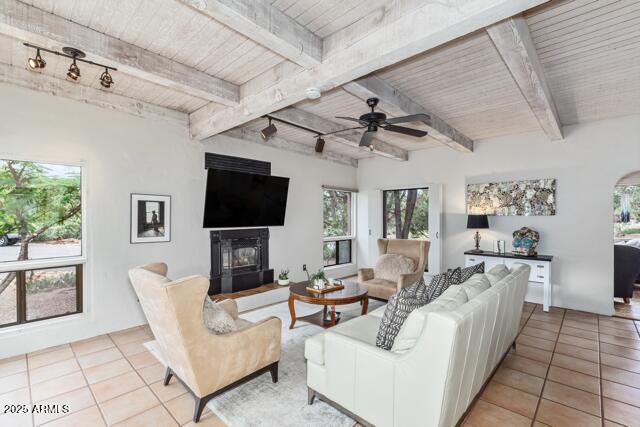 25 Edgewood Cir, Sedona, AZ 86336 - living area with track lighting, wood ceiling with exposed beams, a glass covered fireplace, light tile patterned flooring, and ceiling fan