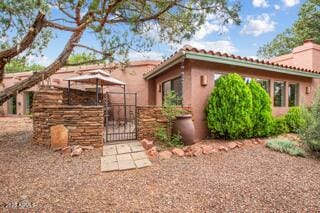 25 Edgewood Cir, Sedona, AZ 86336 - rear view of property with a gate, stucco siding, a tile roof, and a chimney