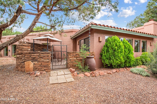 25 Edgewood Cir, Sedona, AZ 86336 - view of side of property featuring a gate, stucco siding, a chimney, and a tile roof
