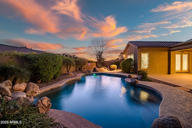 2207 W Hidden Treasure Way, Phoenix, AZ 85086 - pool at dusk with french doors, a patio area, and a fenced backyard