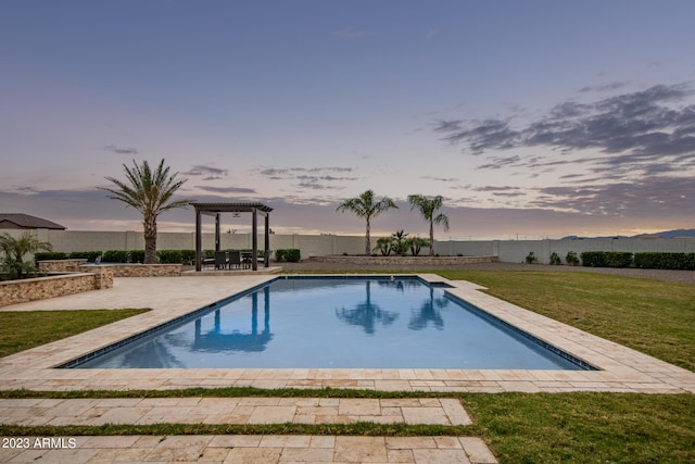 pool at dusk with a yard and a patio