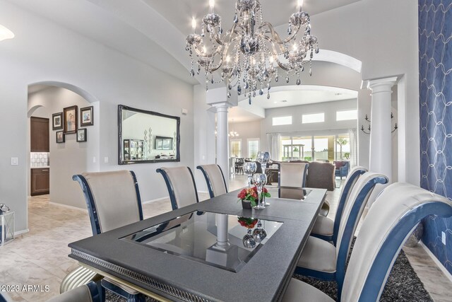 tiled dining area featuring high vaulted ceiling, decorative columns, and a notable chandelier