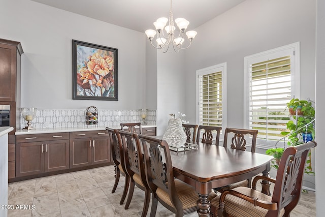 tiled dining area featuring a notable chandelier and vaulted ceiling