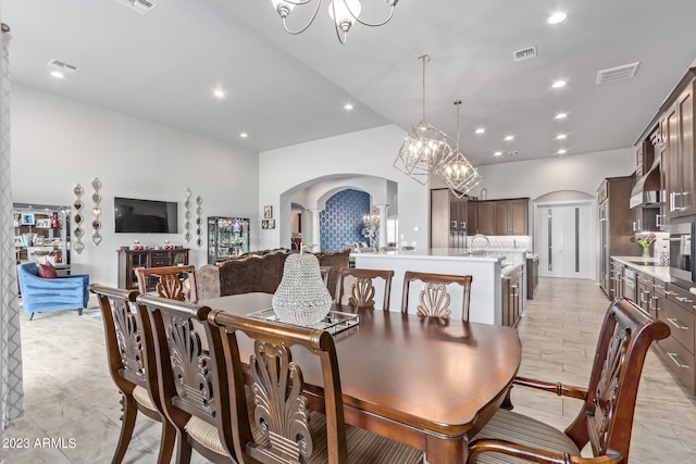 tiled dining area with an inviting chandelier, sink, and decorative columns