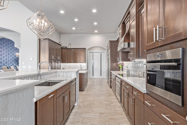 kitchen featuring oven, decorative light fixtures, black electric cooktop, sink, and tasteful backsplash