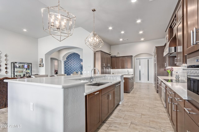 kitchen with an island with sink, tasteful backsplash, pendant lighting, and sink