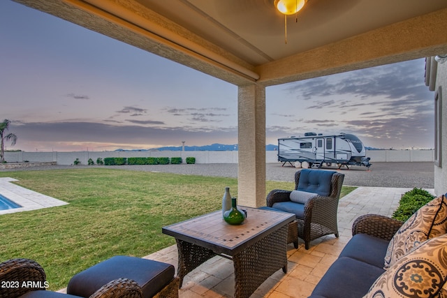 patio terrace at dusk with an outdoor living space and a yard