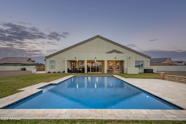 pool at dusk featuring a lawn and a patio