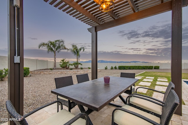 patio terrace at dusk with a pergola, a water view, and a lawn