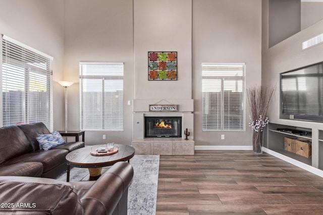 living room with a tile fireplace and a towering ceiling