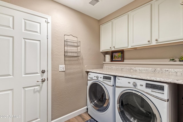 laundry area with cabinets, washer and dryer, and light hardwood / wood-style floors