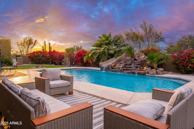 pool at dusk with pool water feature, an outdoor living space, a water slide, and a patio