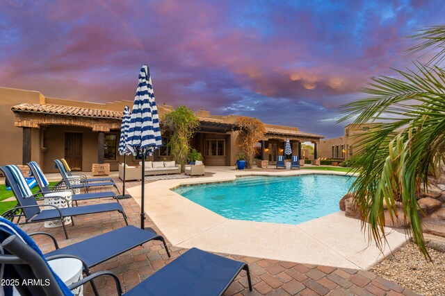 pool at dusk with a patio area