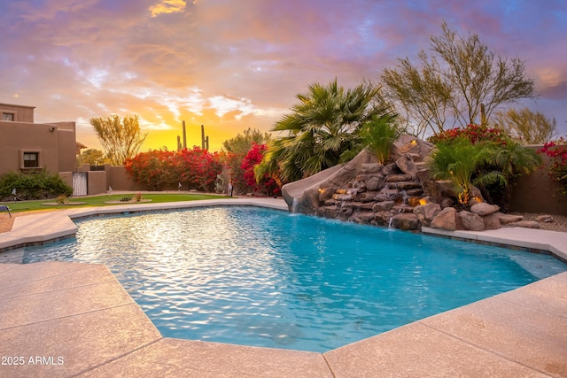 pool at dusk with pool water feature and a water slide