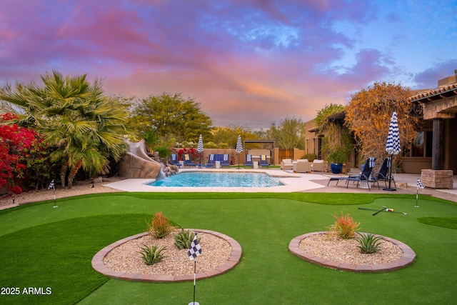 pool at dusk featuring outdoor lounge area, a patio, and a water slide