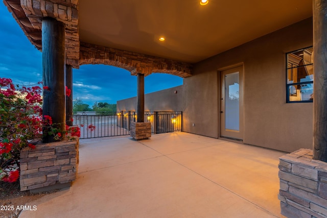 patio terrace at dusk featuring a balcony