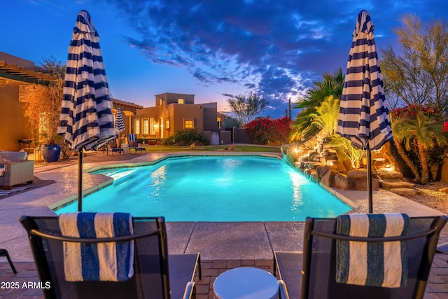 pool at dusk featuring a patio