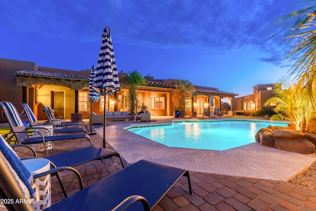 pool at dusk with an outdoor hangout area and a patio area