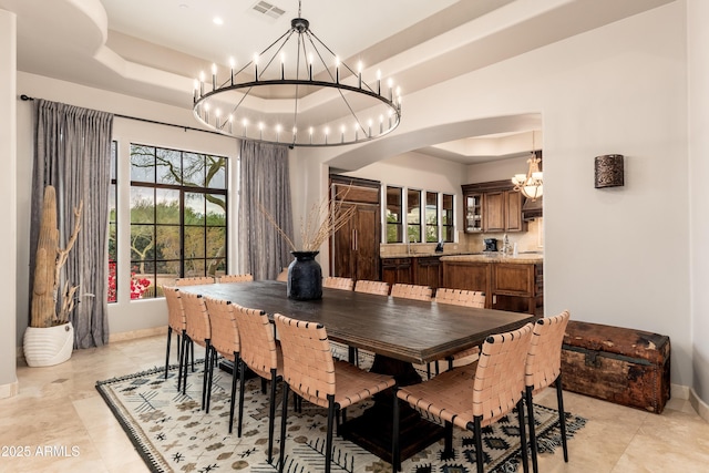 dining room with an inviting chandelier and a raised ceiling