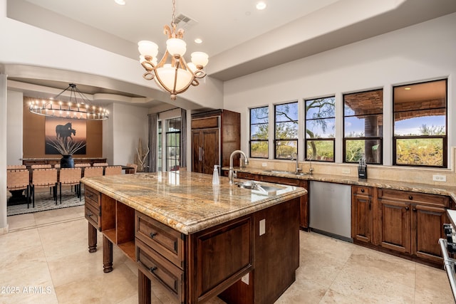 kitchen with light stone counters, decorative light fixtures, stainless steel dishwasher, a notable chandelier, and a kitchen island with sink