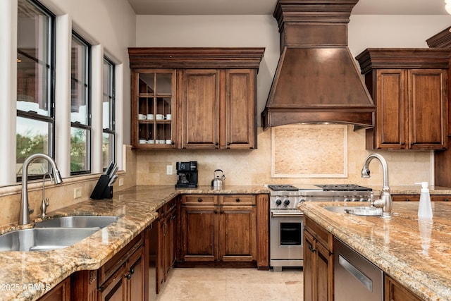 kitchen with premium range hood, sink, light stone counters, appliances with stainless steel finishes, and decorative backsplash