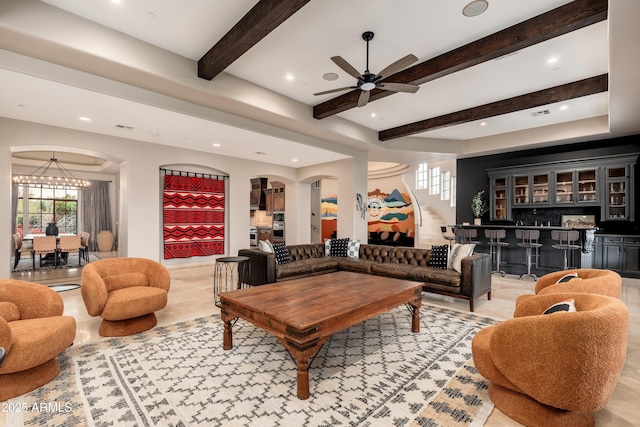 living room featuring bar area and ceiling fan with notable chandelier