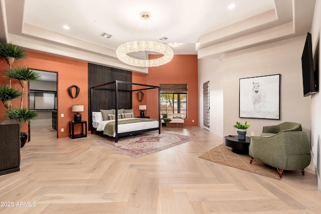 bedroom with light parquet flooring and a tray ceiling