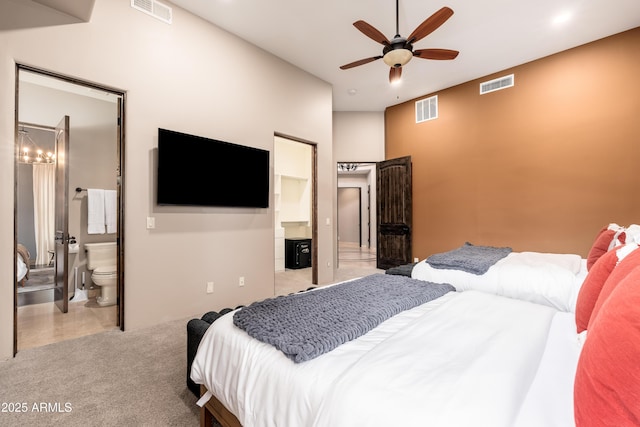 bedroom with ceiling fan, light colored carpet, and ensuite bath