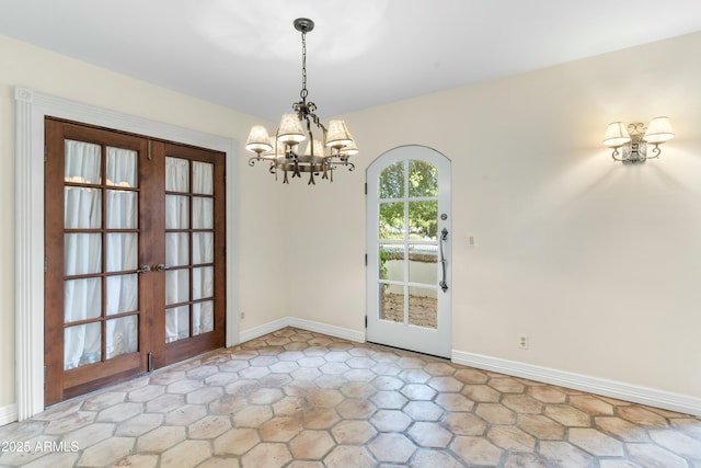 unfurnished dining area featuring a notable chandelier and french doors