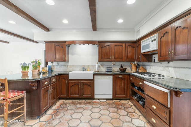 kitchen with beamed ceiling, sink, dark stone countertops, kitchen peninsula, and white appliances