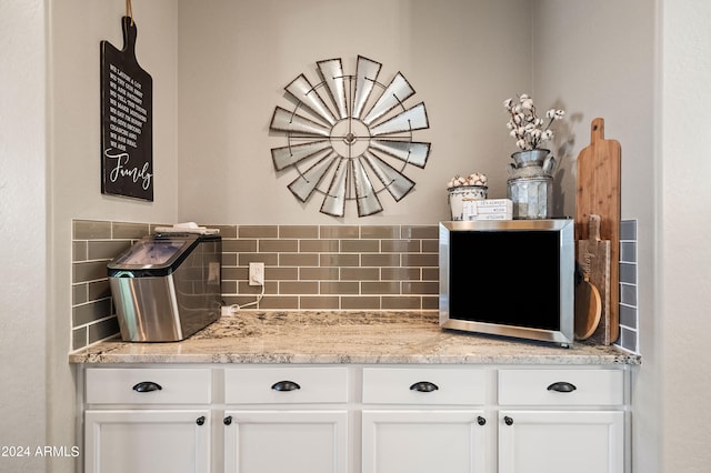 interior space with white cabinets, light stone counters, and backsplash