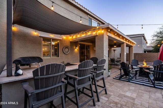 patio terrace at dusk featuring a bar and an outdoor fire pit