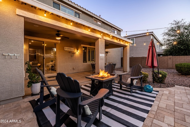 patio terrace at dusk with ceiling fan and a fire pit