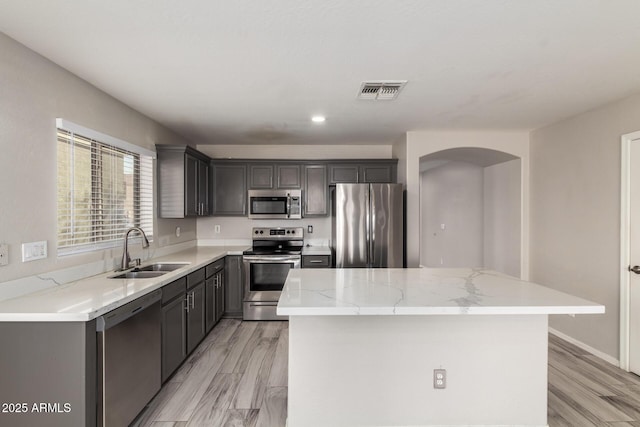 kitchen with arched walkways, stainless steel appliances, a sink, visible vents, and a center island