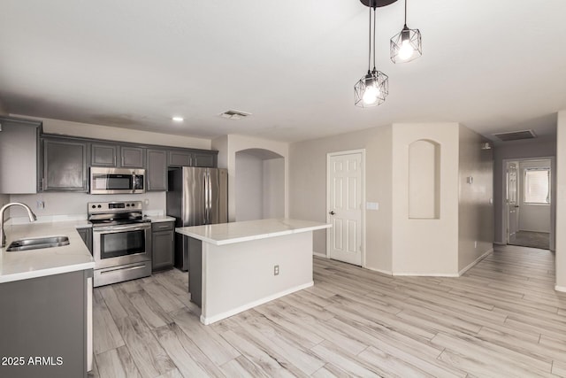 kitchen with a center island, light countertops, visible vents, appliances with stainless steel finishes, and a sink