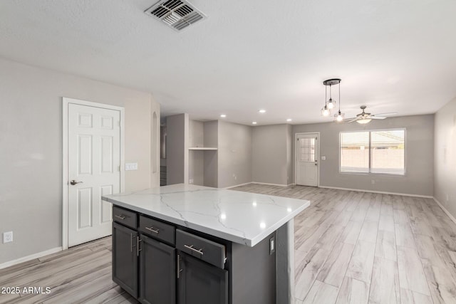 kitchen with open floor plan, light wood-style flooring, a kitchen island, and visible vents